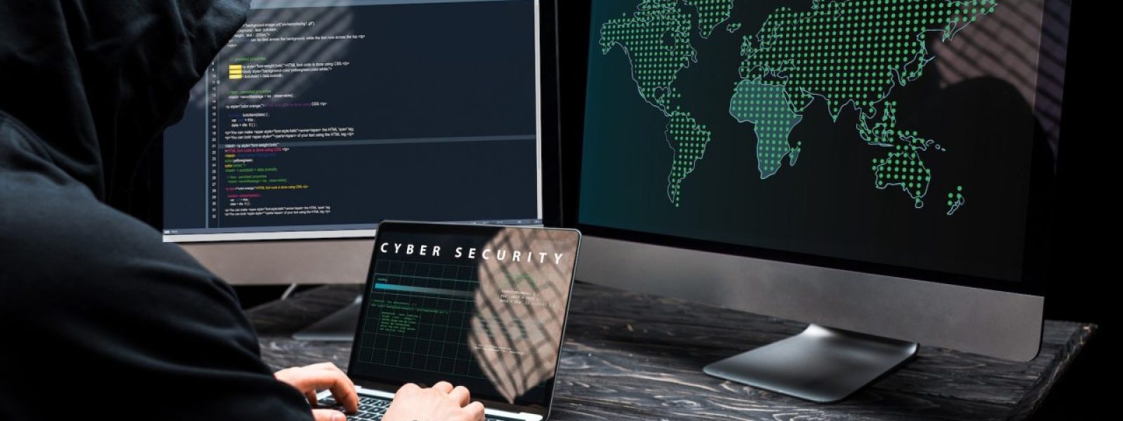 hacker-using-laptop-with-cyber-security-lettering-on-screen-near-computer-monitors-on-black.jpg
